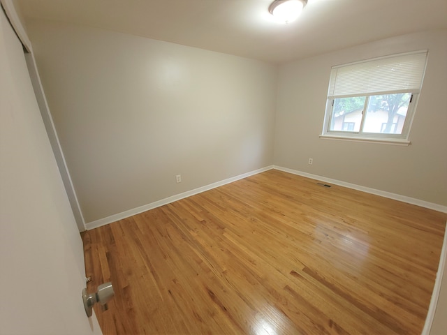 spare room featuring light wood-type flooring, visible vents, and baseboards