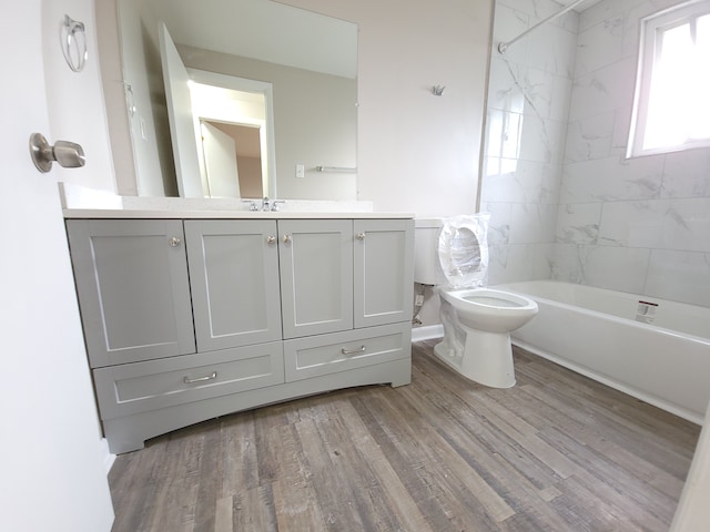 full bath with toilet, bathing tub / shower combination, wood finished floors, and vanity