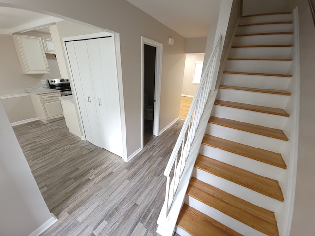 stairs featuring arched walkways, baseboards, and wood finished floors