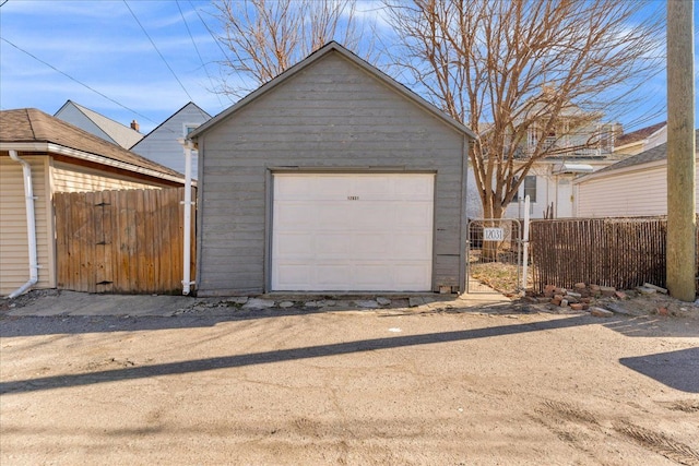 detached garage with a gate, driveway, and fence