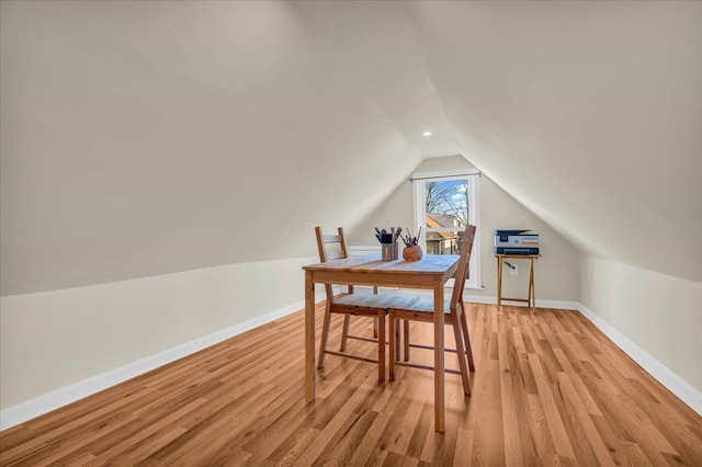 dining space with vaulted ceiling, baseboards, and light wood-type flooring