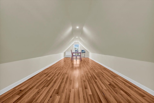 bonus room with light wood finished floors, baseboards, and vaulted ceiling