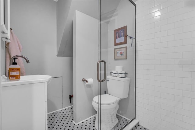 bathroom featuring tile patterned floors, tiled shower, toilet, and a sink