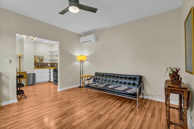 living area featuring ceiling fan, baseboards, light wood-type flooring, and a wall mounted AC