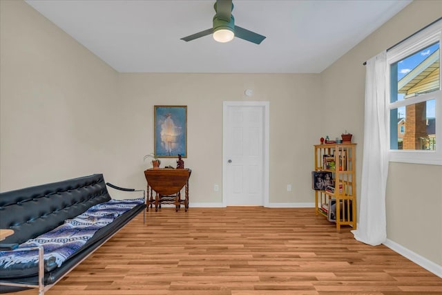 sitting room with light wood-style flooring, a ceiling fan, and baseboards