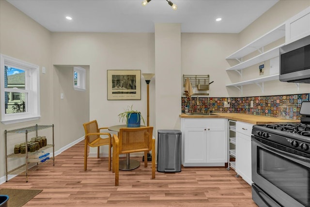 kitchen featuring open shelves, white cabinets, light wood-type flooring, and appliances with stainless steel finishes