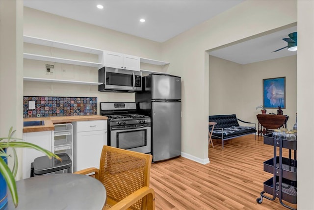 kitchen with open shelves, white cabinets, appliances with stainless steel finishes, and wooden counters