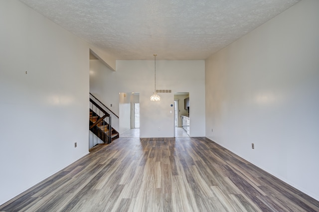 interior space with visible vents, stairway, a textured ceiling, and wood finished floors