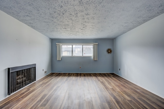 unfurnished living room featuring a textured ceiling and wood finished floors