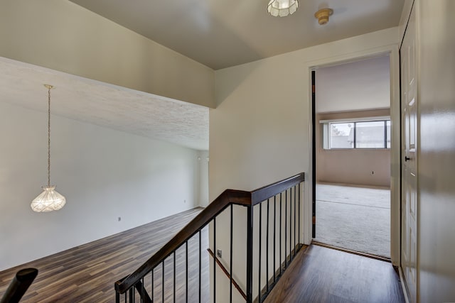 hall with wood finished floors and an upstairs landing