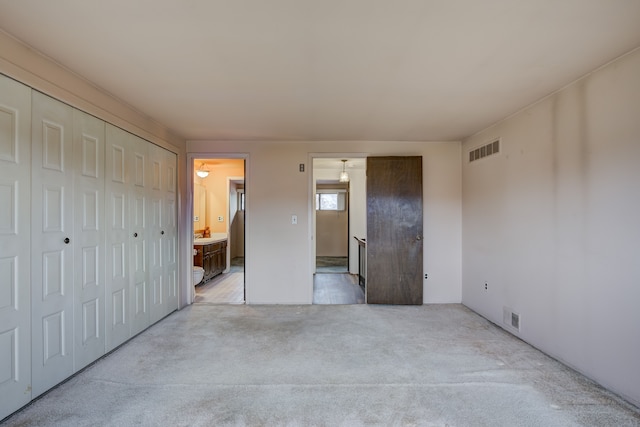 unfurnished bedroom featuring a closet, visible vents, and ensuite bathroom