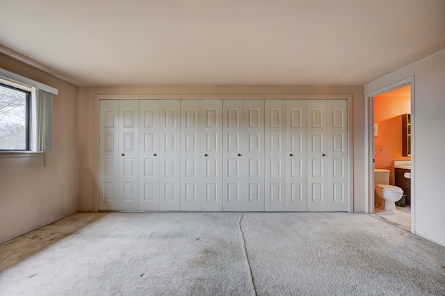 unfurnished bedroom with ensuite bathroom and carpet