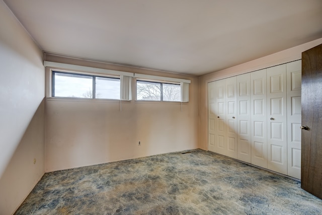 unfurnished bedroom featuring a closet, multiple windows, and carpet floors