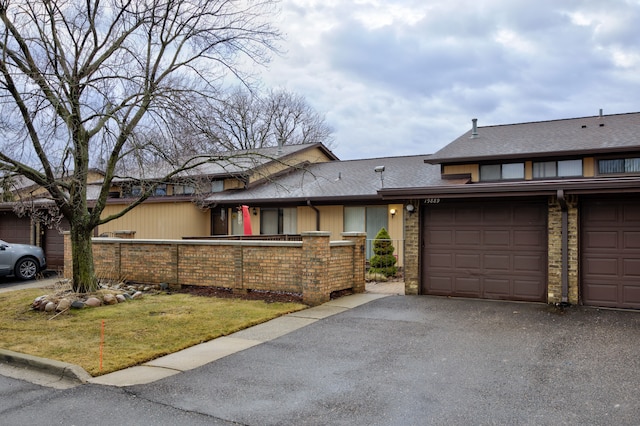 view of front of home featuring a fenced front yard, a garage, roof with shingles, and driveway