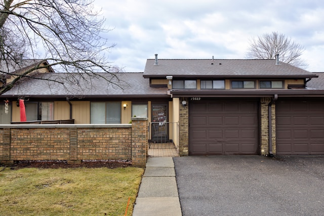 view of front of home with a garage, driveway, and a shingled roof