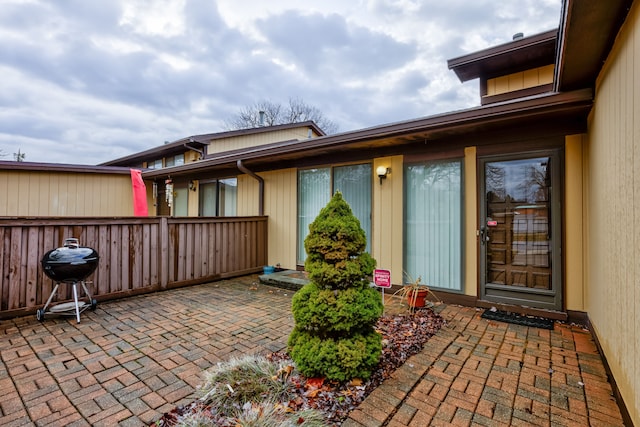 view of exterior entry featuring a patio and fence