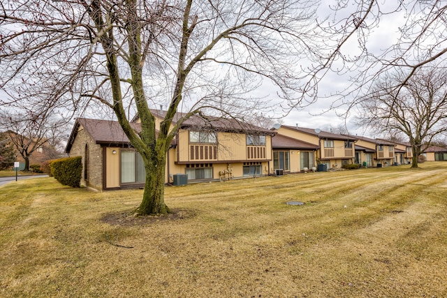 back of house featuring brick siding, a lawn, and central AC