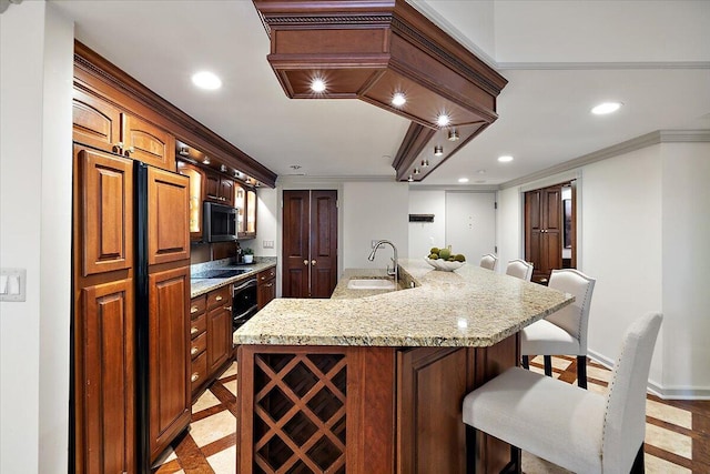 kitchen featuring a kitchen island with sink, recessed lighting, a breakfast bar, a sink, and stainless steel microwave