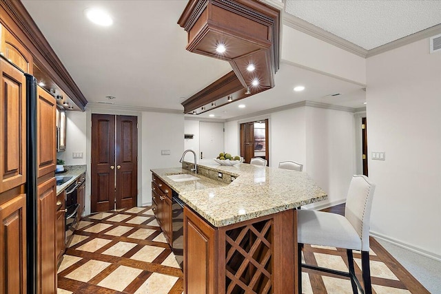 kitchen with baseboards, an island with sink, a kitchen breakfast bar, a sink, and recessed lighting