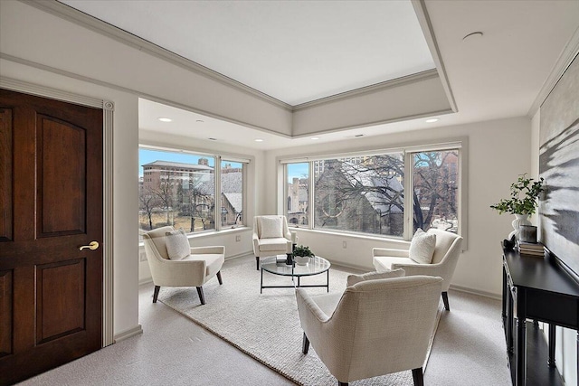 living area featuring baseboards, crown molding, a raised ceiling, and recessed lighting