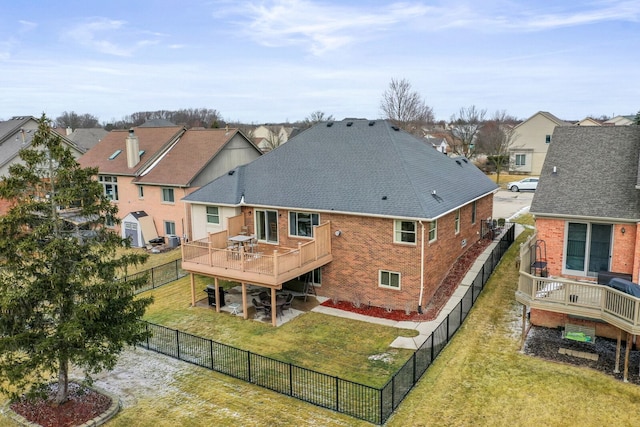 back of house with a fenced backyard, brick siding, a shingled roof, a lawn, and a wooden deck