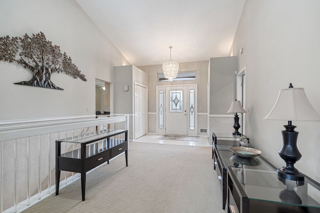 carpeted entryway featuring a chandelier, vaulted ceiling, wainscoting, and visible vents