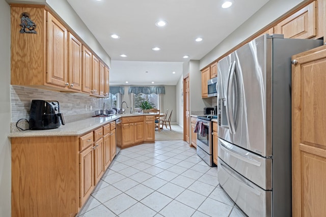 kitchen with light tile patterned floors, tasteful backsplash, appliances with stainless steel finishes, a peninsula, and light countertops