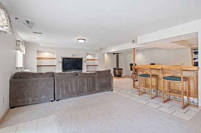 tiled living area with carpet, a dry bar, recessed lighting, visible vents, and a wood stove