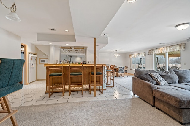 interior space featuring light carpet, visible vents, open floor plan, and light tile patterned flooring