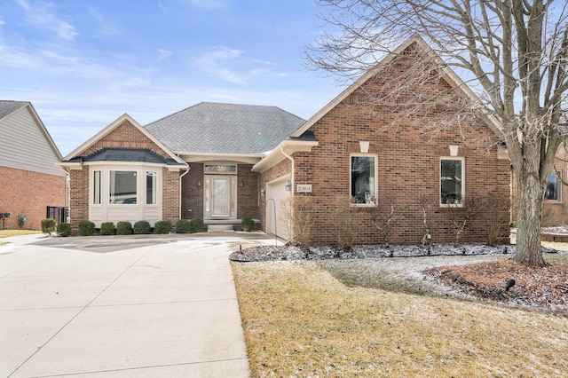 view of front facade featuring an attached garage, a shingled roof, concrete driveway, and brick siding