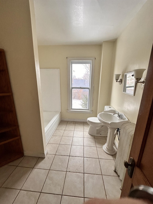 full bathroom featuring radiator, a tub to relax in, toilet, and tile patterned floors