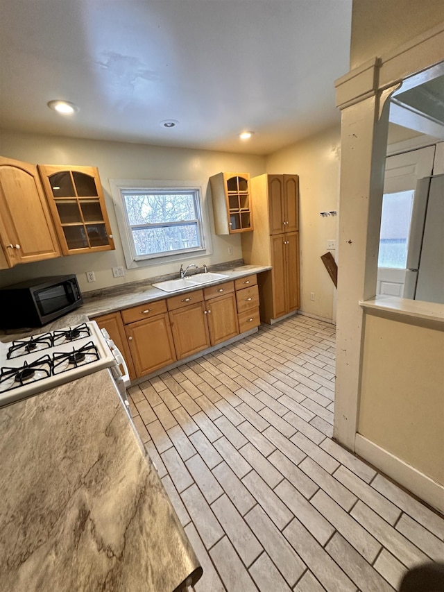 kitchen with glass insert cabinets, white appliances, light countertops, and a sink