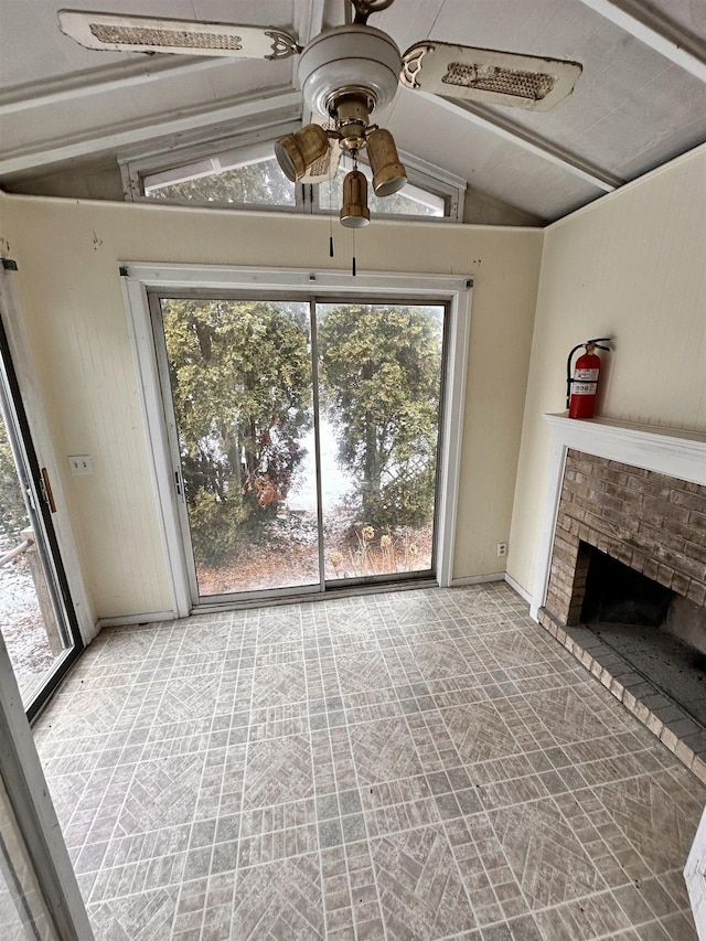 unfurnished living room featuring a brick fireplace, plenty of natural light, vaulted ceiling, and a ceiling fan