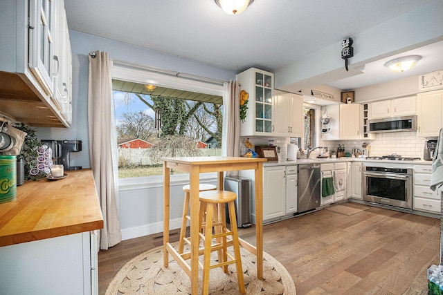 kitchen with light wood finished floors, appliances with stainless steel finishes, backsplash, and white cabinetry