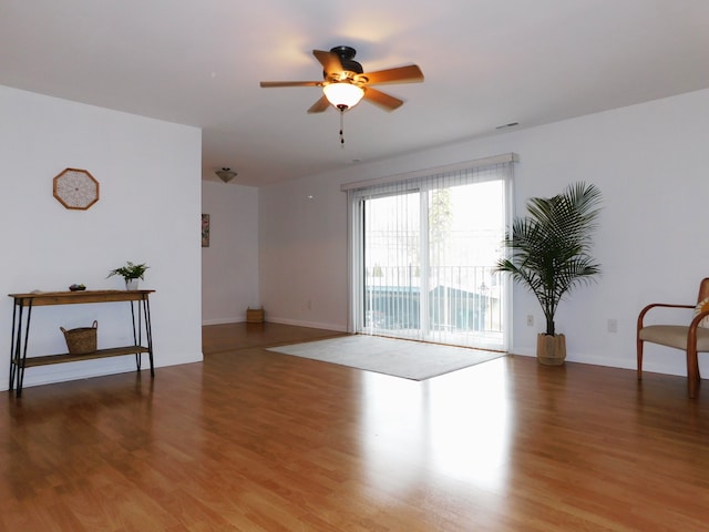 unfurnished room with wood finished floors, a ceiling fan, and baseboards