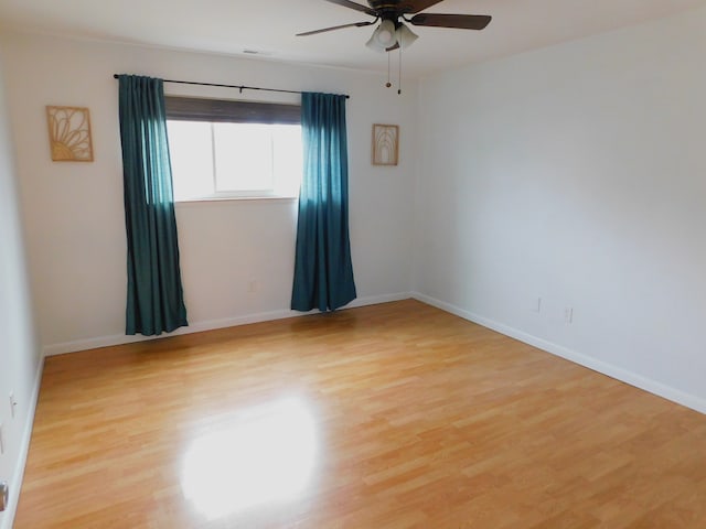 spare room with a ceiling fan, light wood-type flooring, and baseboards