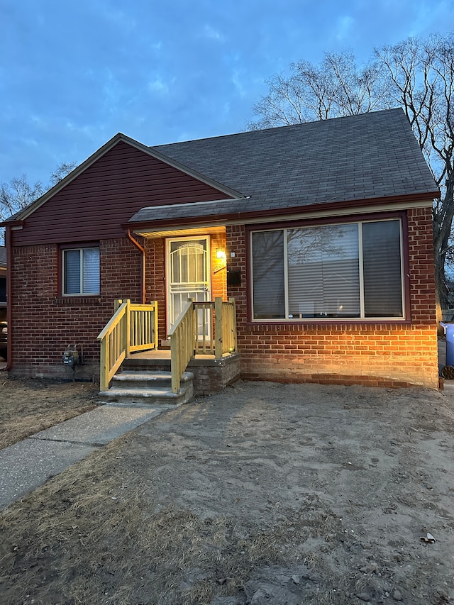 view of front of property featuring a shingled roof and brick siding