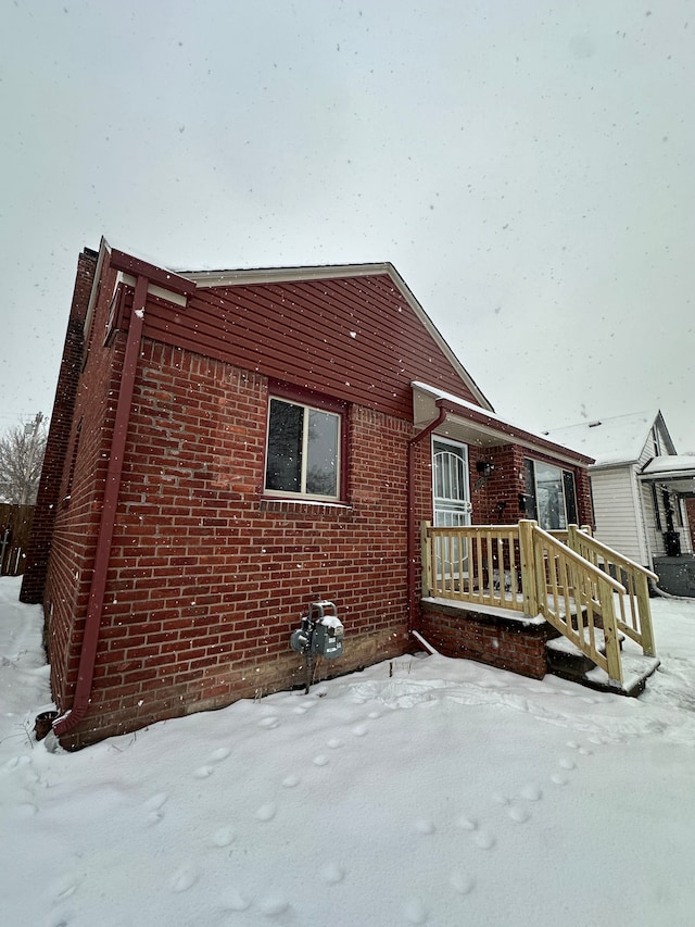 view of snow covered exterior with brick siding