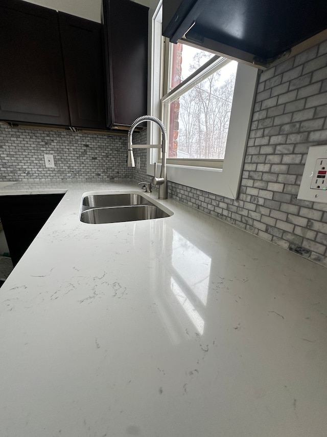 kitchen featuring dark cabinetry, a sink, and tasteful backsplash