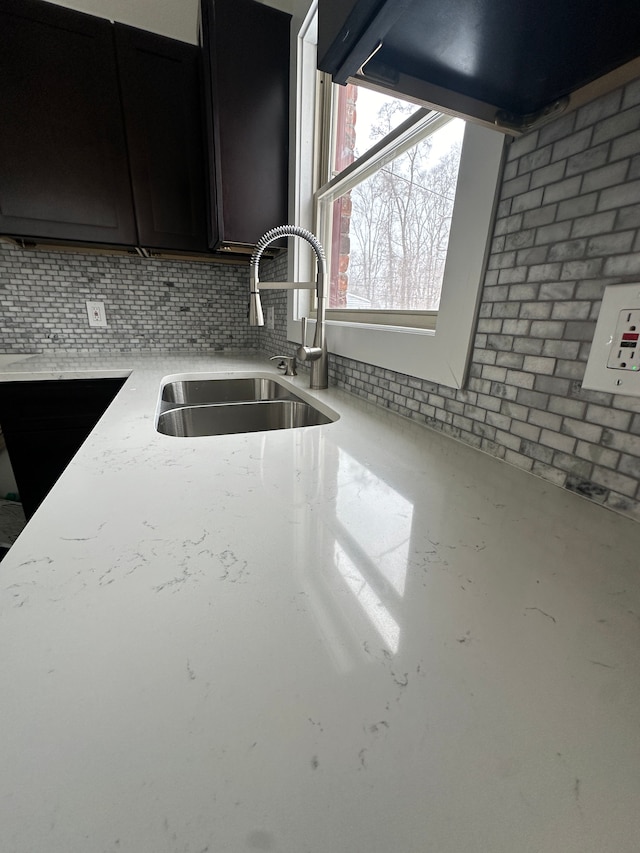 kitchen with backsplash, a sink, and dark cabinets