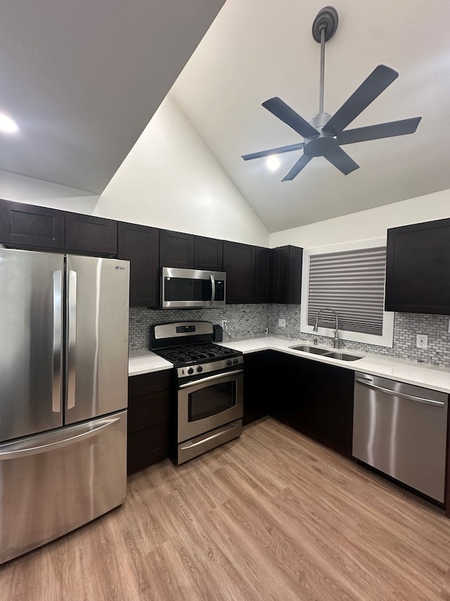 kitchen featuring stainless steel appliances, light countertops, dark cabinetry, and a sink