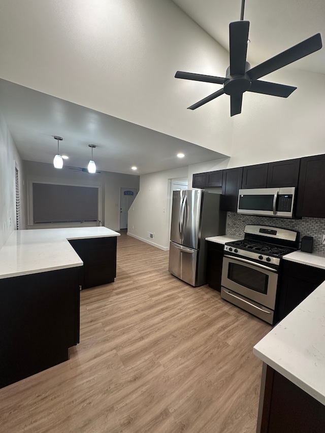 kitchen with stainless steel appliances, light wood-type flooring, decorative backsplash, and dark cabinets