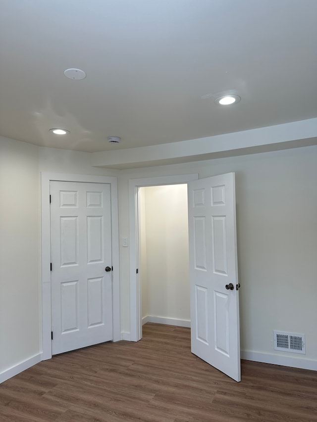 empty room with wood finished floors, recessed lighting, baseboards, and visible vents