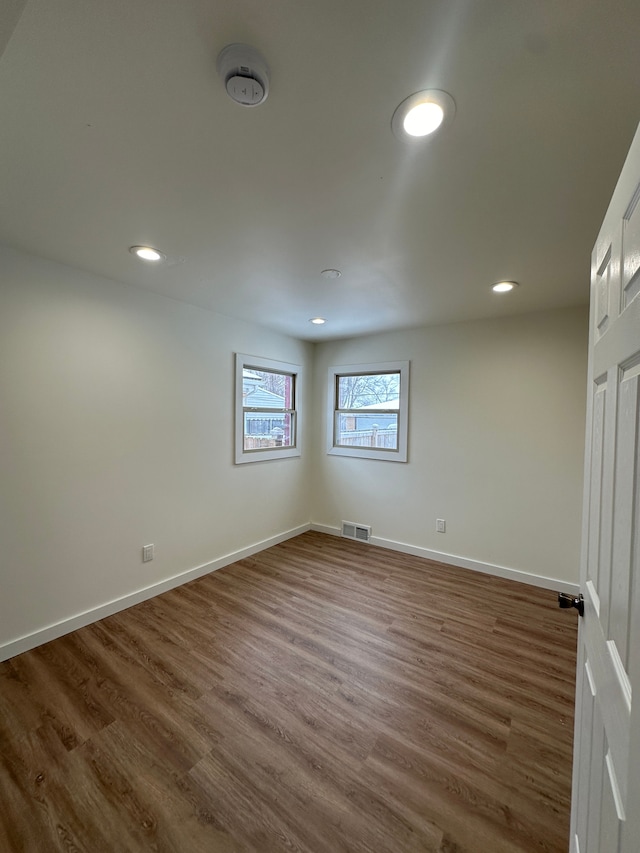 empty room featuring visible vents, dark wood finished floors, and baseboards