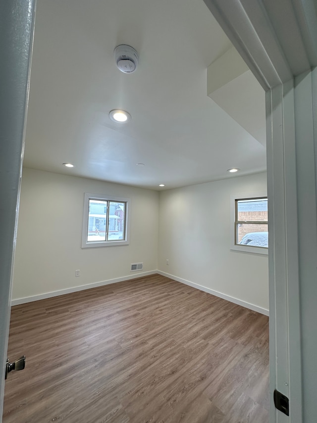 spare room featuring a wealth of natural light, visible vents, baseboards, and wood finished floors