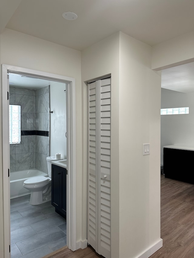 bathroom with washtub / shower combination, vanity, toilet, and wood finished floors