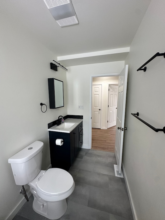 half bath featuring baseboards, visible vents, toilet, and vanity