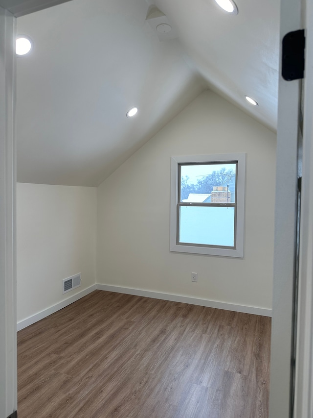 bonus room featuring lofted ceiling, wood finished floors, visible vents, and baseboards