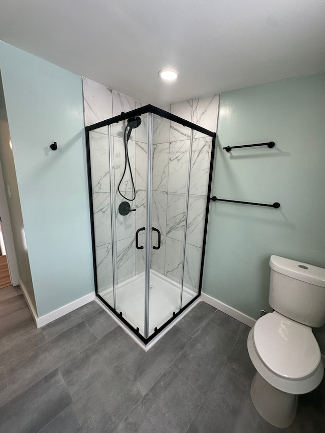 bathroom featuring a stall shower, baseboards, and toilet