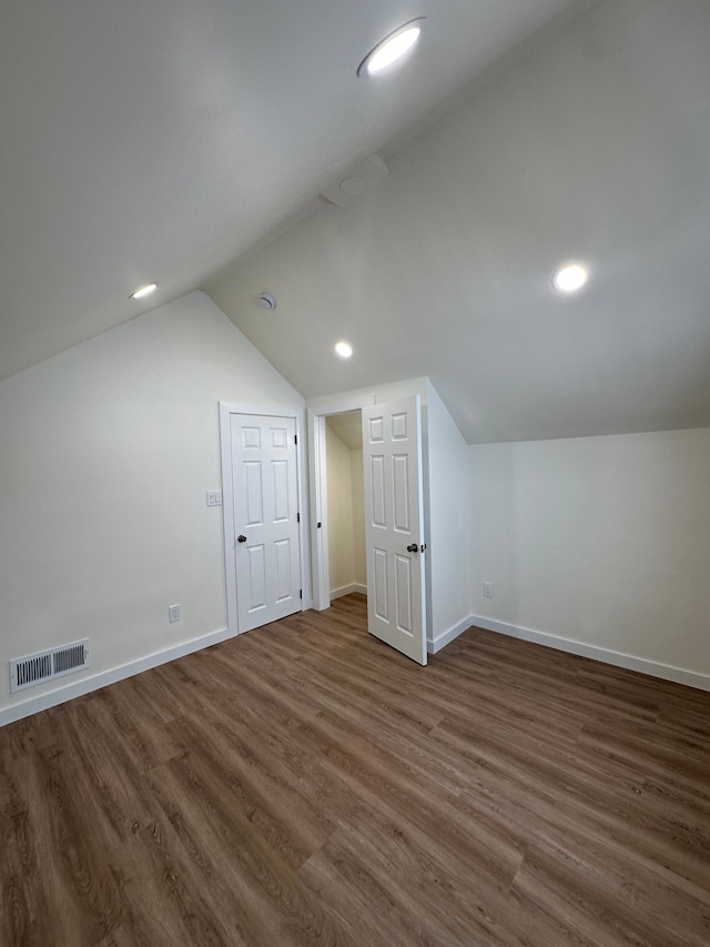 additional living space featuring dark wood-style flooring, visible vents, baseboards, recessed lighting, and vaulted ceiling
